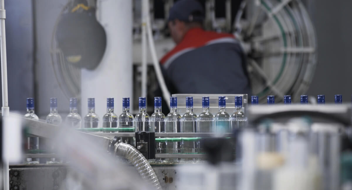 Fragment maszyny butelkującej z widocznym siłownikiem lub chwytakiem