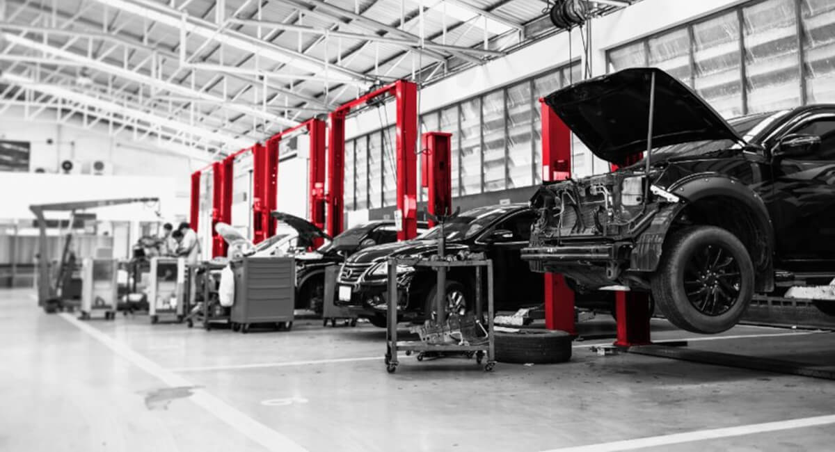 Widok na duży warsztat samochodowy z wieloma stanowiskami, symbolizujący profesjonalne centrum serwisowe