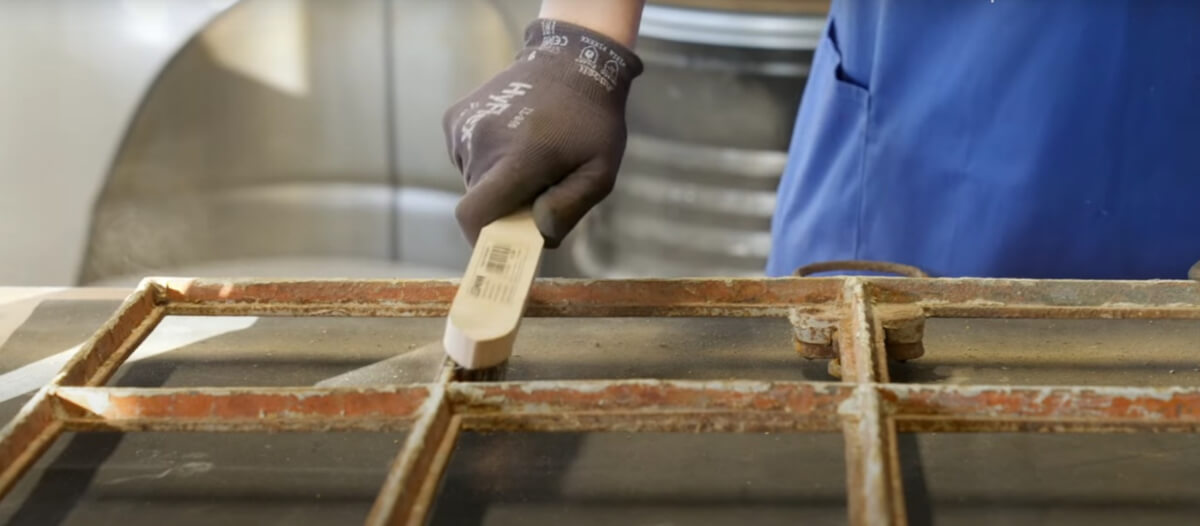 Szorowanie zardzewiałej ramy okna szczotką drucianą