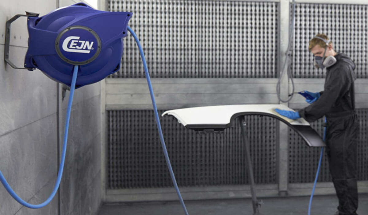 Lakiernik malujący element karoserii za pomocą pneumatycznego pistoletu lakierniczego