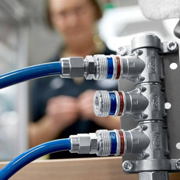 Rozdzielacz z szybkozłączami na stanowisku montażowym Operator w tle przy rozdzielaczu wyposażonym w bezpieczne szybkozłącza CEJN eSafe