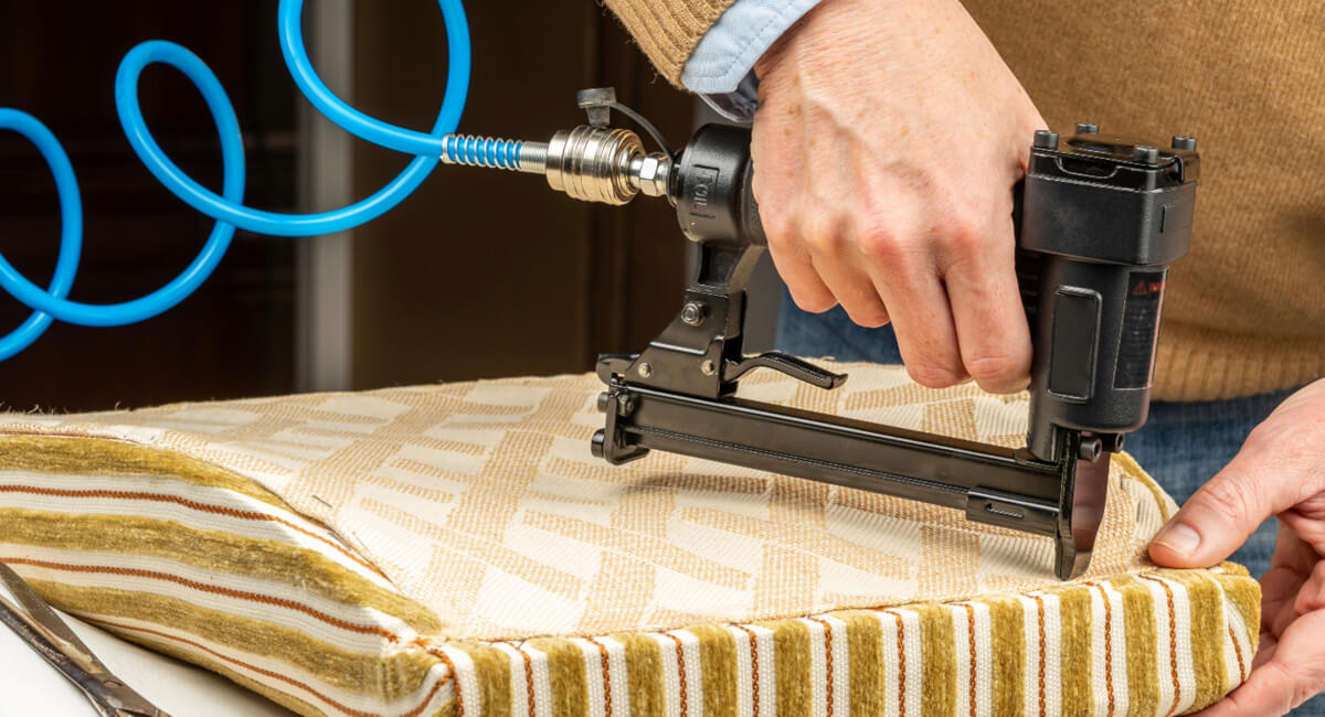 Serwisant używający gwoździarki pneumatycznej do montażu tapicerki meblowej